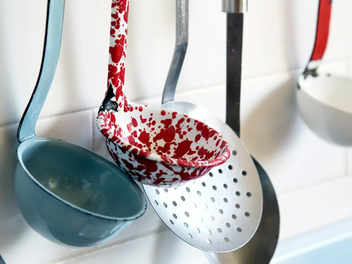 Enamel ladles and a skimmer hanging on a wall